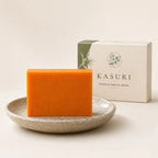 Savon orange au kaki du Japon Kasuri dans une coupelle en céramique, devant son étui